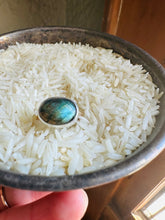 Load image into Gallery viewer, Incredible flashy blue Labradorite Statement ring.  A chunky Silver bezel encircles oval blue Labradorite on a hammered 14k Gold Fill Band. Ring is shown, held by the artist, in a vintage silver dish full of rice.
