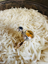 Load image into Gallery viewer, Oval Citrine Cabochon Ring with Blue Sapphire and Silver Accents. Organic hammered statement ring set with 14k Gold Fill Band. Ring displayed in a vintage silver bowl of white rice.
