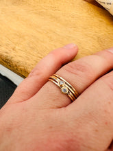 Load image into Gallery viewer, Artist’s hand wearing two 14k Gold Fill Dew Drop rings, stacked with two hammered 14k Gold Fill Sweet Nothing Bands.
