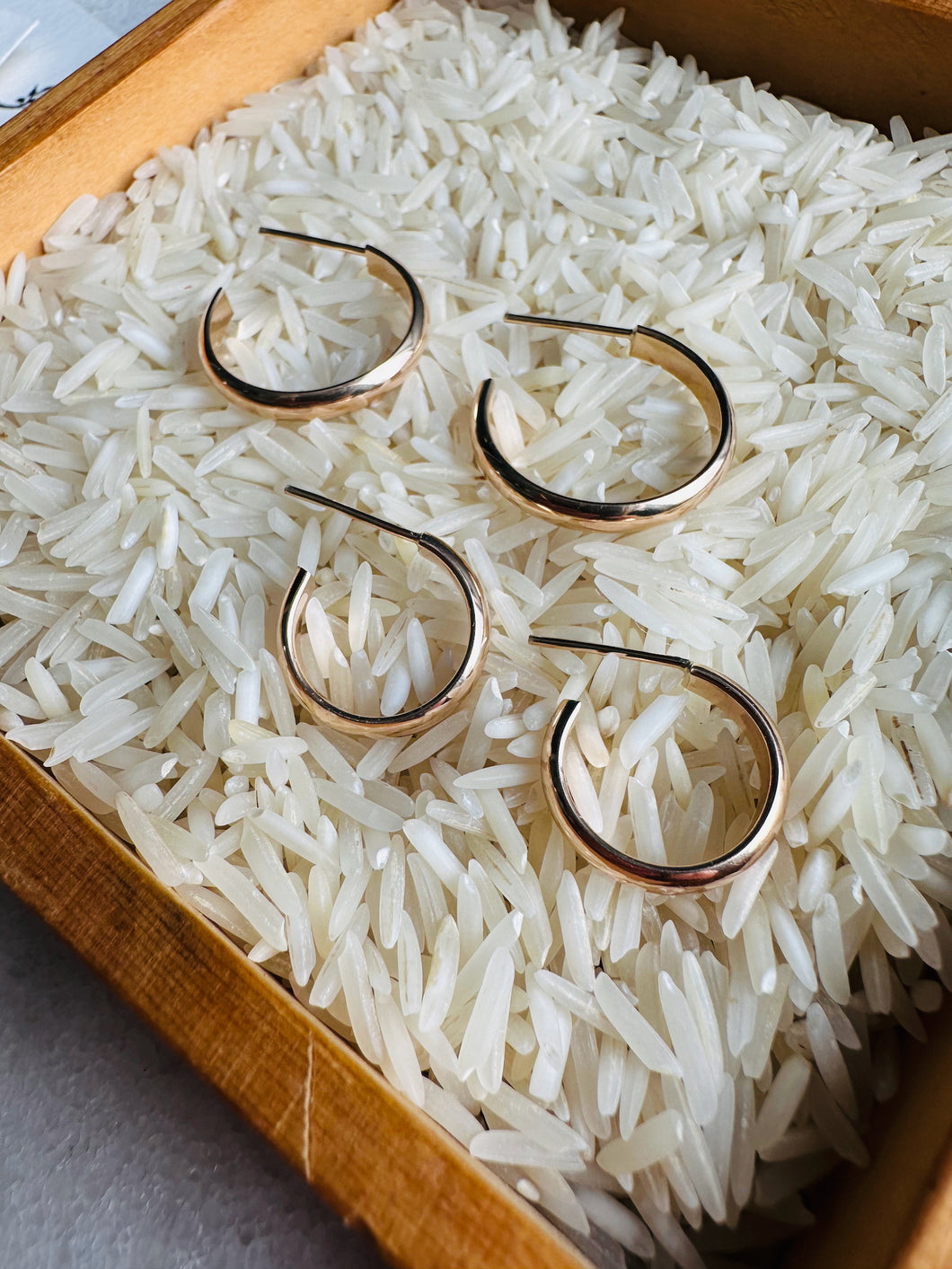 14k Gold Filled Classic 90s Hoops shown in both sizes in a bed of white rice