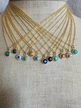 Load image into Gallery viewer, Set of gold necklaces with small, round evil eye charms on a natural linen mannequin bust.
