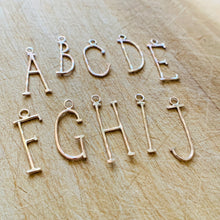 Load image into Gallery viewer, Hammered Gold Fill Lovely Letter initial Charms A through J on a rustic wood background. 
