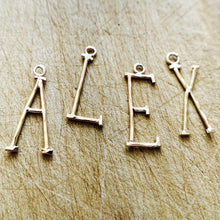 Load image into Gallery viewer, Handmade 14k Gold Fill Initial Charms spelling out the name Alex on a rustic wood background.
