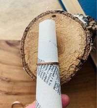 Load image into Gallery viewer, 14k Gold Fill Country Roads Band Ring Shown on cone of vintage dictionary paper on round of paper birch wood.
