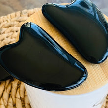 Load image into Gallery viewer, Pair of Black onyx Gua Sha Massage Stones on a blonde bamboo pedastal.
