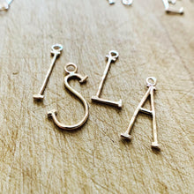 Load image into Gallery viewer, Hammered Gold Fill lovely Letter charms spelling out the name Isla on a rustic wood background. 
