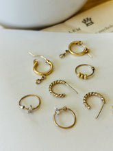 Load image into Gallery viewer, Scattered collection of Notions of Lovely Mini Hoops resting on an old book with coffee. Earrings shown are 14k Gold Fill Sparkling Huggie Hoops, Mini Rope Hoops, Glow Infinity Hoops and Starlet Infinity Hoops.

