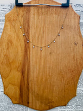 Load image into Gallery viewer, 14k Gold Fill Misty Morning Necklace with tiny dangling Cubic Zirconia Droplets draped on a natural wood clipboard

