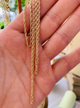 Load image into Gallery viewer, Strands of 14k Gold Fill Chain hanging from the artists hand.
