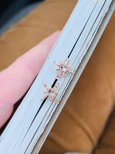 Load image into Gallery viewer, 14k Gold Fill Star Crossed Lover Earrings tucked into the edge of a book. Gold Starburst Stud earrings have Cubic Zirconia centers.
